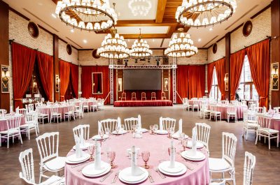 restaurant-hall-with-small-stage-monitor-red-curtains-brick-walls-white-napoleon-chairs
